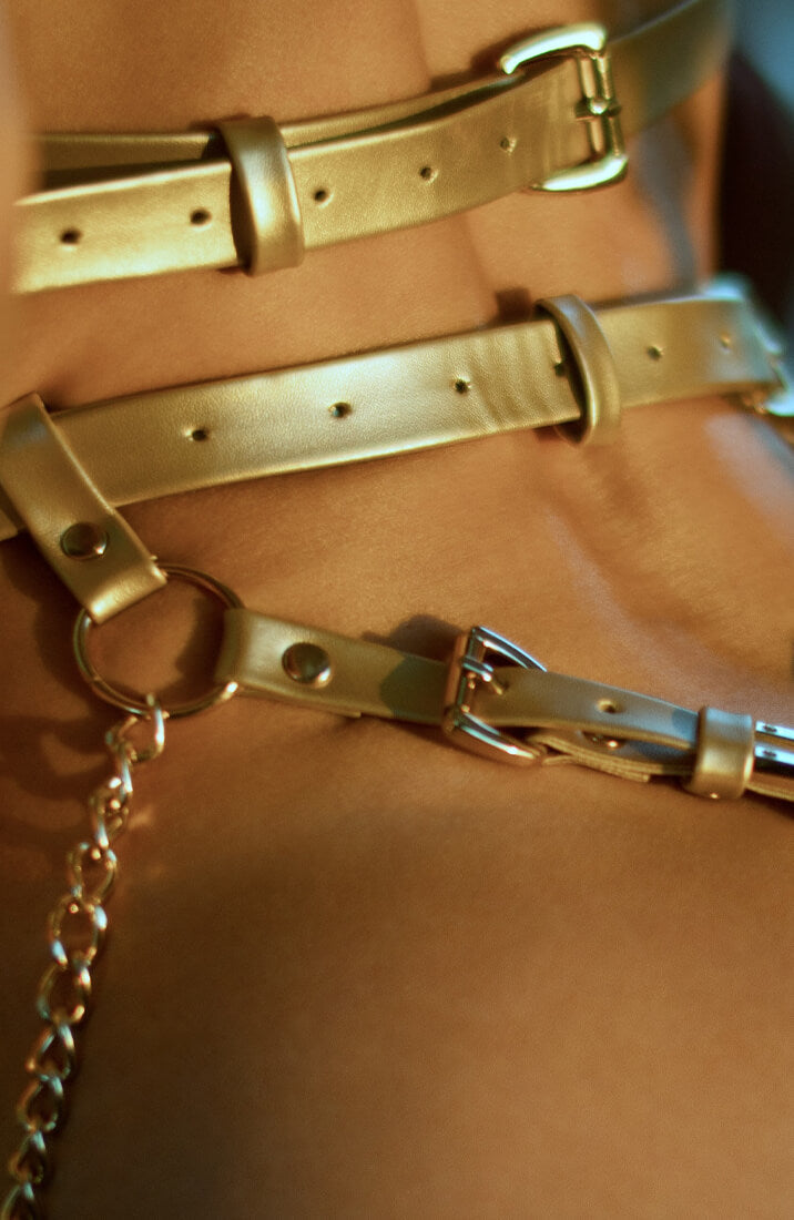 Guldskinnende body harness med justerbare stropper og kæder ved hofterne